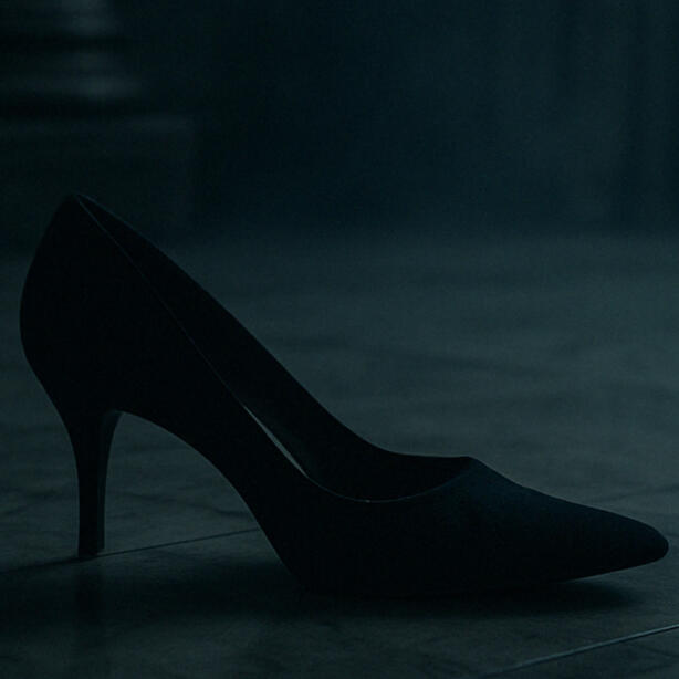 Black high-heeled shoe on a dark castle floor.
